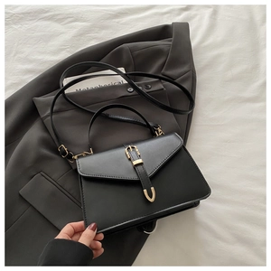 Detail of matte black square bag with gold buckle on a stylish dark grey blazer