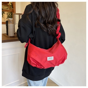 Macro shot of red ruched hobo bag featuring a gathered strap and fashion logo label