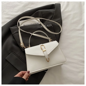 Detail of white faux leather crossbody bag with gold buckle and removable strap