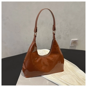 Detail of glossy brown patent leather hobo bag with gold metal ring and zipper closure