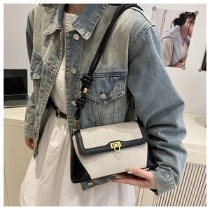 Detail of a chic patchwork crossbody bag with beige canvas, black leather, and gold lock