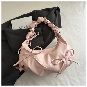 Detailed view of pink shoulder bag featuring decorative bows and ruched handles texture