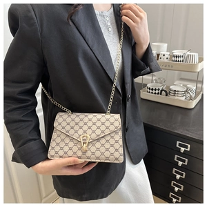 Détail du sac à bandoulière vintage avec boucle fer à cheval dorée sur blazer noir