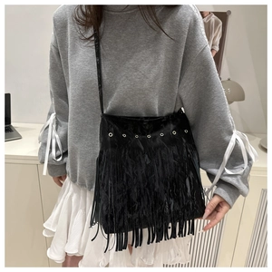 Détail d'un sac bandoulière noir à franges avec œillets porté par un mannequin