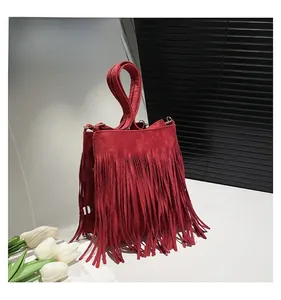 Détail du sac seau en daim rouge avec de longues franges et anneaux dorés en métal