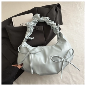 Detail of light blue shoulder bag featuring sweet bows and pleated handle textures
