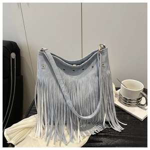 Gros plan sur un sac cabas bleu clair en denim avec de longues franges et œillets