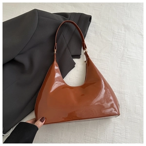 Detailopname van bruine lakleren hobo-tas met goudkleurige details op stof