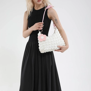 White popcorn textured crossbody bag with pink rope strap and floral charm accessory