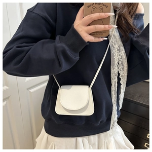 Mini white crossbody bag with pebble leather texture and flap design shown on model