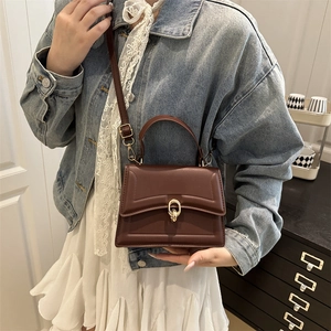 Fashionable dark brown leather handbag with gold lock buckle and adjustable strap