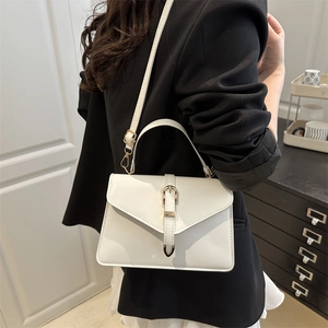 Fashionable white crossbody bag with top handle and belt detail shown on a model
