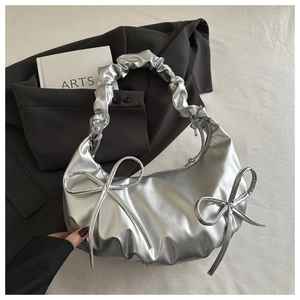 Detail of silver metallic crescent bag featuring ruffled handle and side bow accents