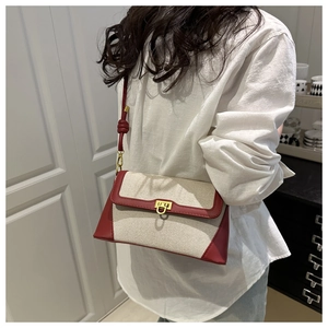 Detail view of contrast color shoulder bag with red trim and gold clasp on a model