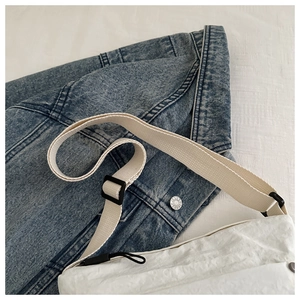 Detail shot of white wrinkled texture nylon crossbody bag with wide canvas shoulder strap