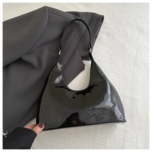 Detail van zwarte laklederen hobo tas met glanzende afwerking op textuurstof