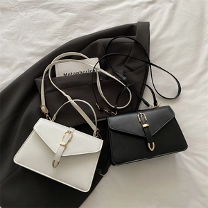 Minimalist solid color crossbody flap bag in black and white with metal buckle detail