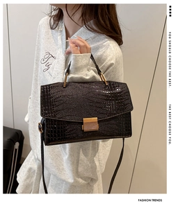 Detail of crossbody bag featuring crocodile texture and golden metal clasp on model