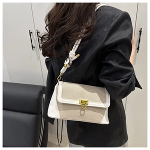 Detail of the chic contrast crossbody bag featuring woven rope strap and gold metal lock