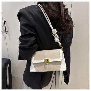 Detail of minimalist contrast shoulder bag with beige fabric and golden swivel clasp