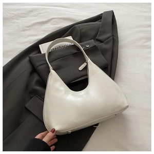 Detail view of cream white crescent shoulder bag with smooth leather texture and silver hardware