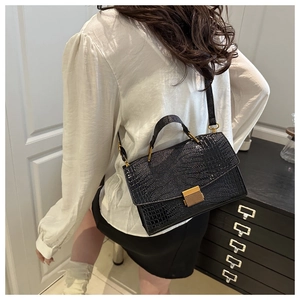 Detail of vintage black crocodile pattern handbag with golden striped metal buckle