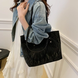 Minimalistische große schwarze Tragetasche mit Faltentextur am Modell im Freizeitlook