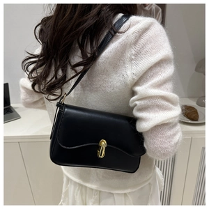 Detail of a black leather shoulder bag with a gold oval twist lock and wavy flap design