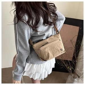 Khaki nylon crossbody bag detail with front flap pocket and round metallic logo