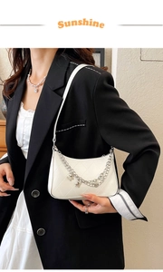 Close-up of white quilted PU leather handbag with silver butterfly chain and strap