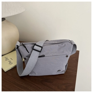 Detail of gray nylon crossbody bag with adjustable strap on a wooden table setup