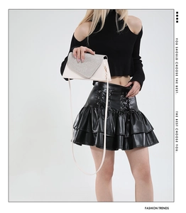 Detail of white envelope evening bag with glitter flap and thin shoulder strap on model