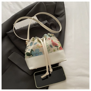 Detail view of floral jacquard bucket bag with leather drawstring and textured fabric
