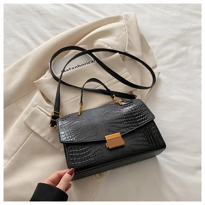 Detail of black crocodile texture leather bag with elegant golden metallic lock closure