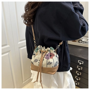Detail of vintage floral drawstring bucket bag worn on shoulder by a model indoors