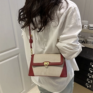 Minimalist cream canvas crossbody bag with burgundy leather trim and gold buckle closure