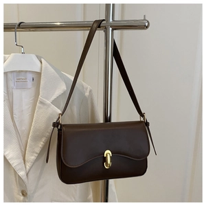 Detail of dark brown matte faux leather handbag with elegant gold metal oval lock closure