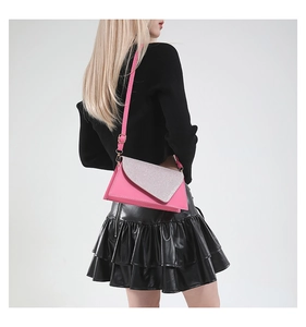 Pink crossbody envelope bag with silver glitter flap worn by a model in studio