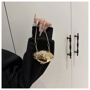 Close-up of golden shell-shaped evening bag with metal chain and textured hammered finish