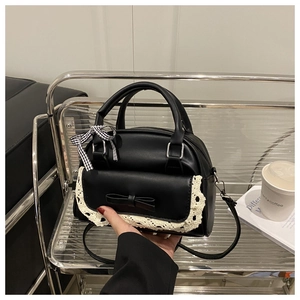 Detail of black crossbody bag with white lace trim and checkered silk scarf handle