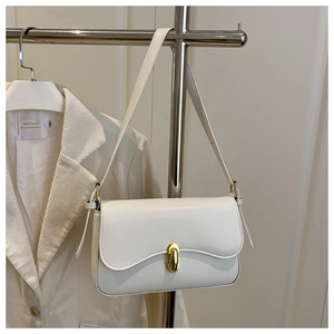 Detail view of white leather shoulder bag with gold metal buckle and thin strap