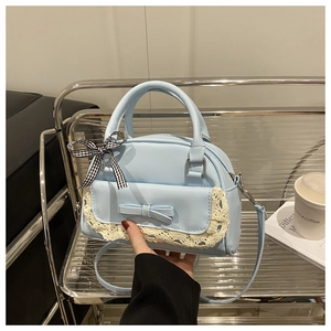 Close-up of light blue lace handbag with decorative bow and checkered ribbon detail