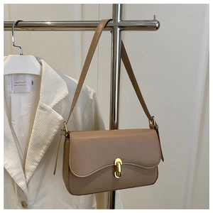 Detail of tan leather shoulder bag featuring a gold capsule-shaped twist lock closure