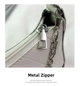Close-up of silver metal zipper and quilted leather texture on white square bag