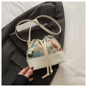 Detail der floralen Gobelin-Beuteltasche mit weißem Lederbesatz und Kordelzugverschluss