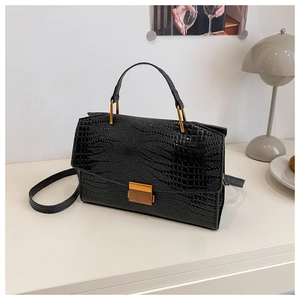 Detail of black faux crocodile texture handbag with gold metal lock and square hardware