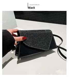 Detail of black asymmetrical handbag with sequined flap and white contrast stitching