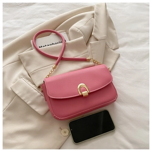 Détail d'un sac à main rose avec boucle dorée et smartphone pour comparer la taille