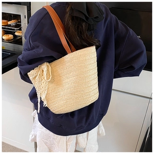 Straw tote bag detail featuring brown leather straps and a large cream lace bow accent