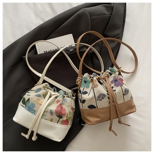 Detail view of drawstring bucket bags featuring floral embroidery in beige and brown colors